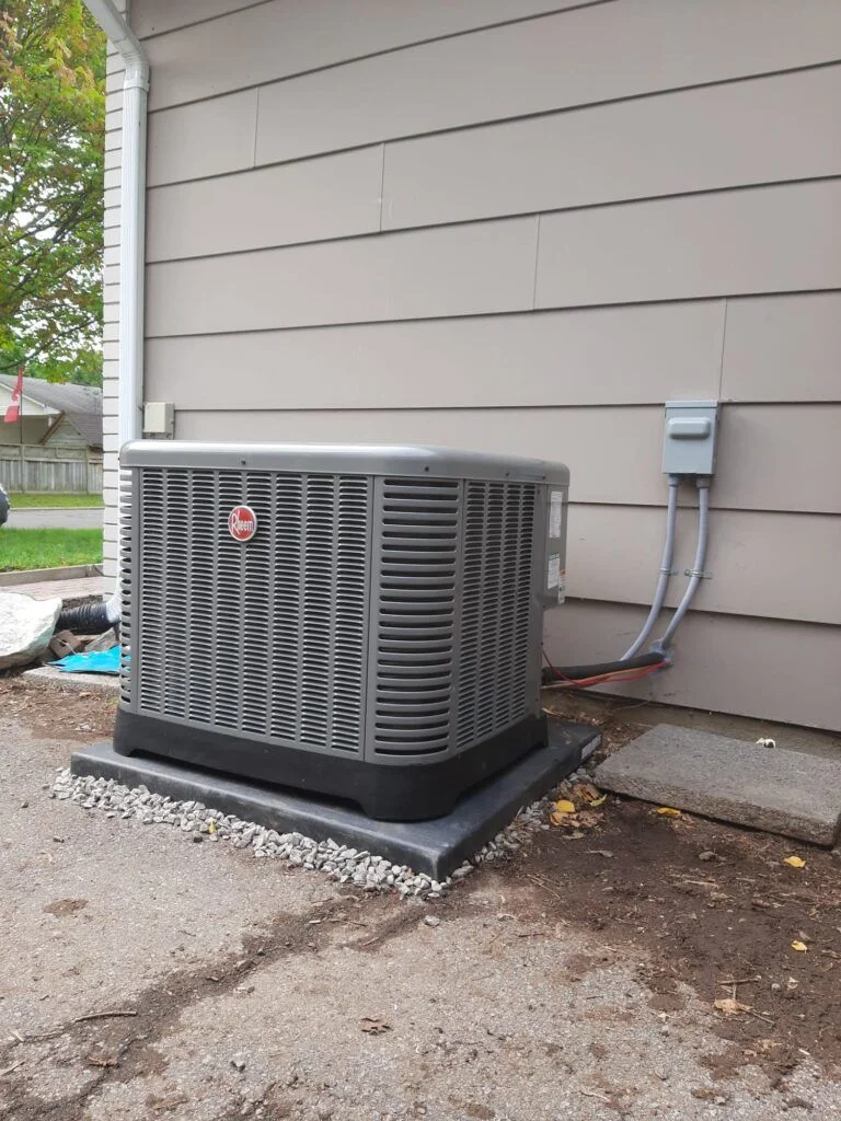 A newly installed residential air conditioning unit positioned on a concrete pad beside a home in Alpharetta, Georgia. A technician from A&K Service Inc. checks the outdoor condenser connections during the post-installation inspection.