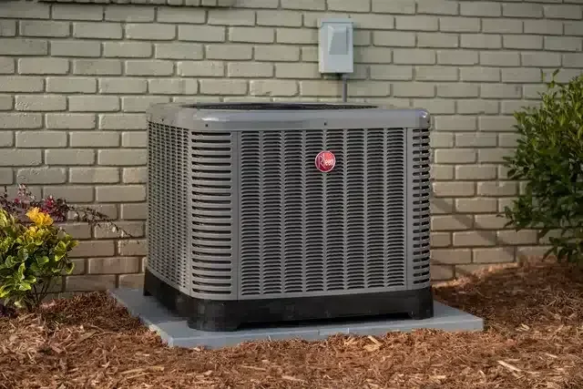 An A&K Service Inc. HVAC technician inspecting and cleaning an outdoor condenser unit at an Alpharetta, GA residential property. The technician checks coil condition and electrical connections during a routine maintenance visit.